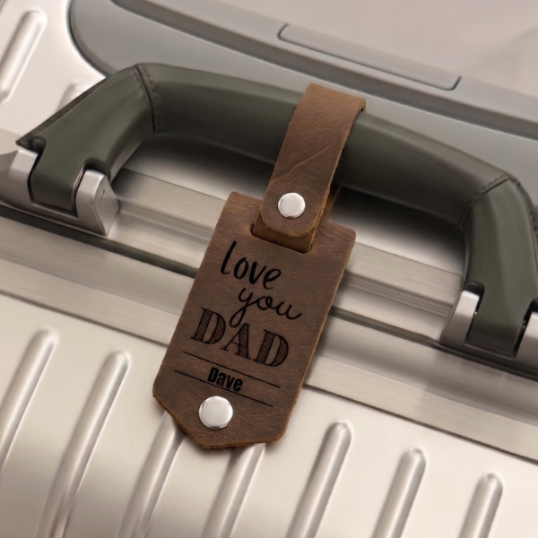 Personalisierter gravierter brauner Leder-Anhänger mit der Aufschrift ‚Love you Dad Dave' an einem silbernen Koffergriff